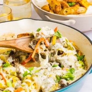 Philly cheesesteak casserole being scooped out with a wooden spoon.