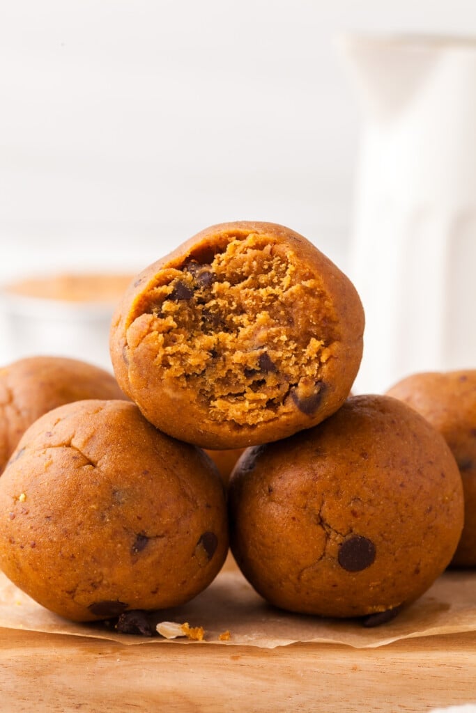 Three pumpkin protein balls with one with a bite taken out of it.