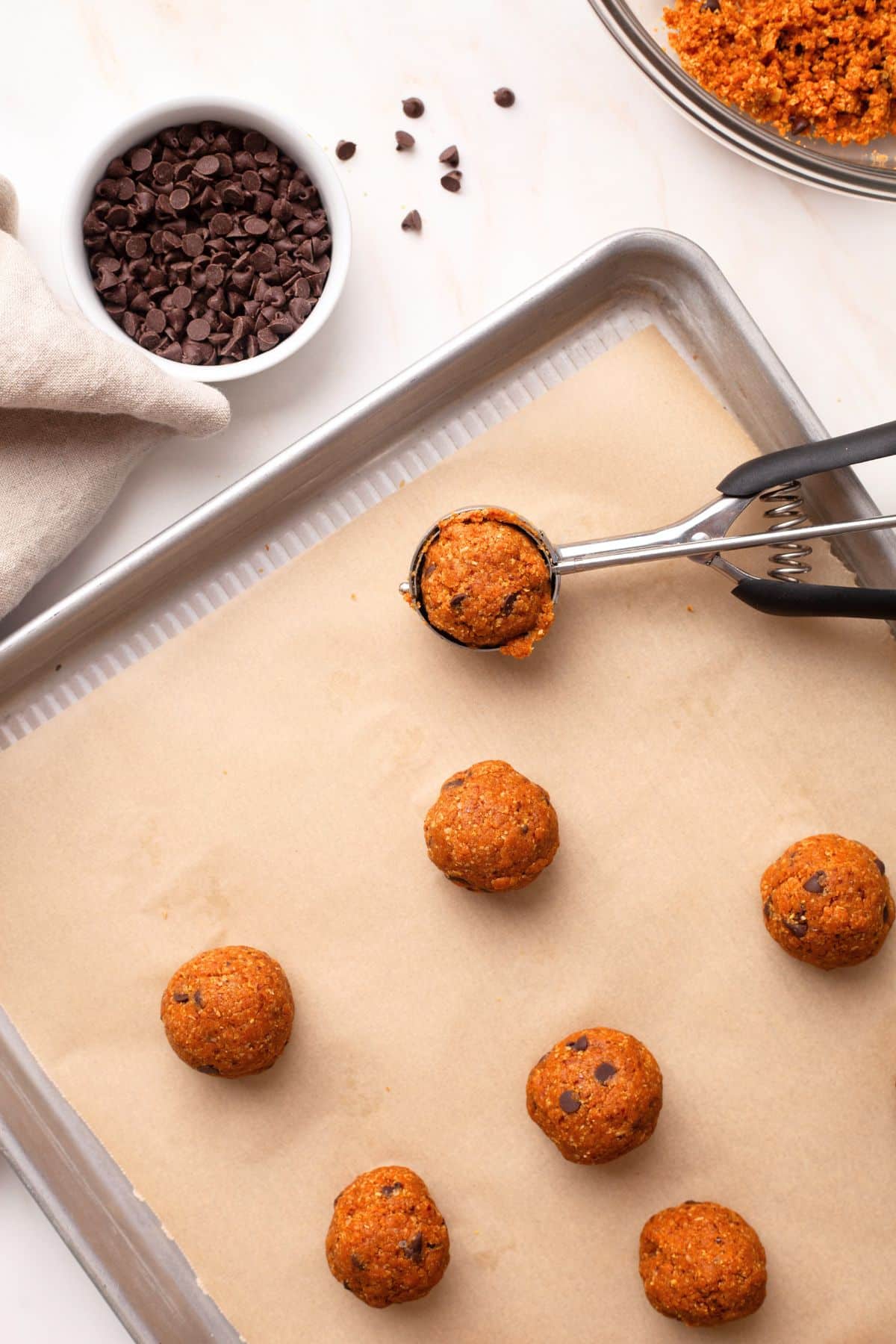 Pumpkin protein balls being rolled on a sheet pan. 