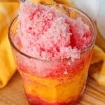 Frozen fruit shaved ice in a clear glass with a spoon.
