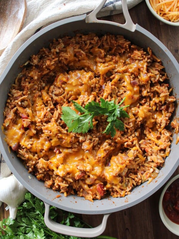 Cheesy taco rice in a skillet garnished with cilantro.