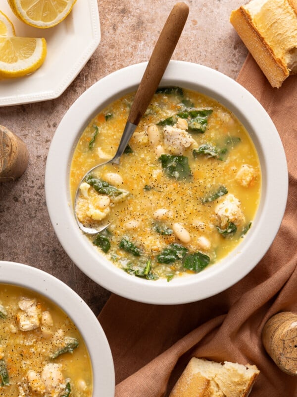 A bowl of chicken cauliflower soup on a countertop with a spoon.