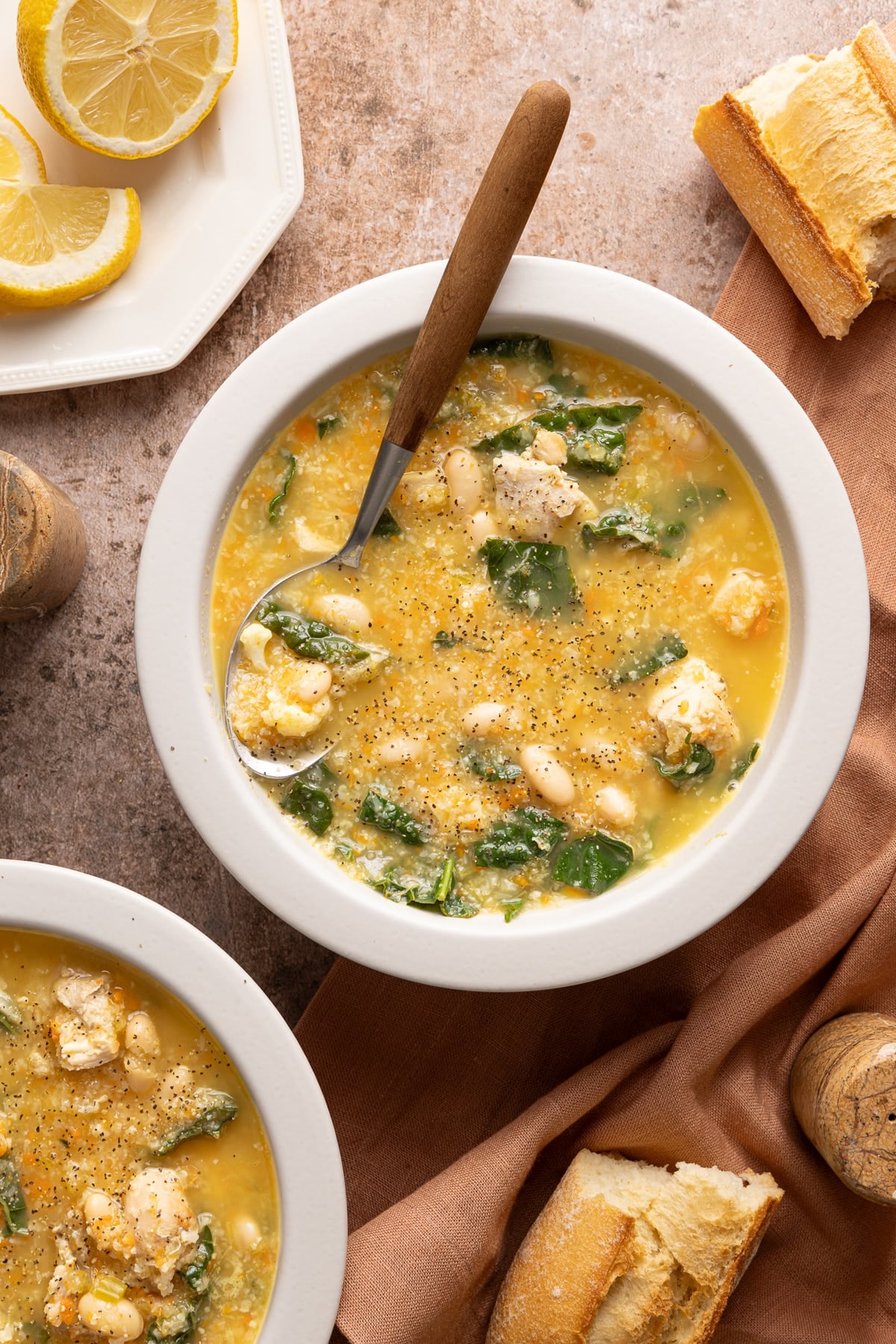 A bowl of chicken cauliflower soup on a countertop with a spoon.