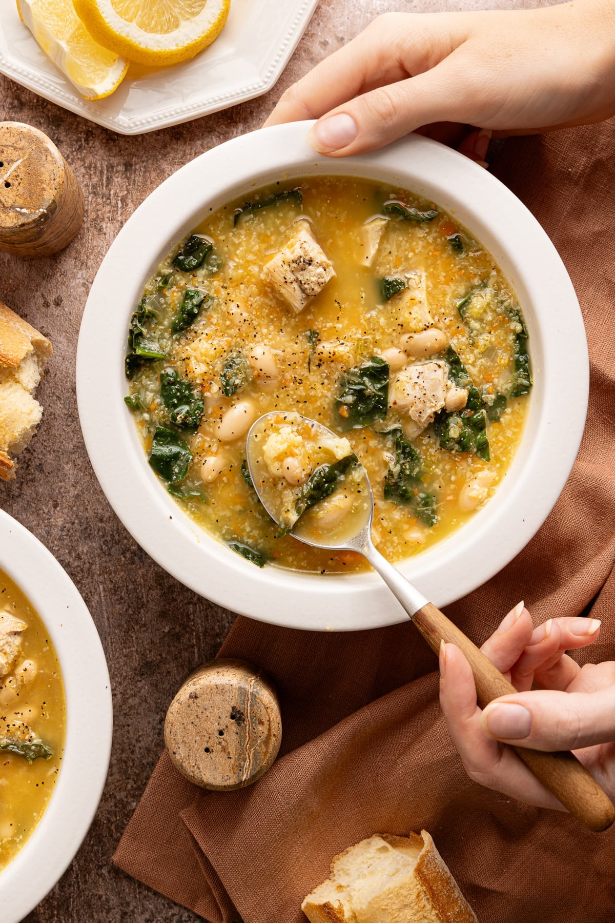 A hand lifts a spoonful of the chicken cauliflower soup from the bowl.