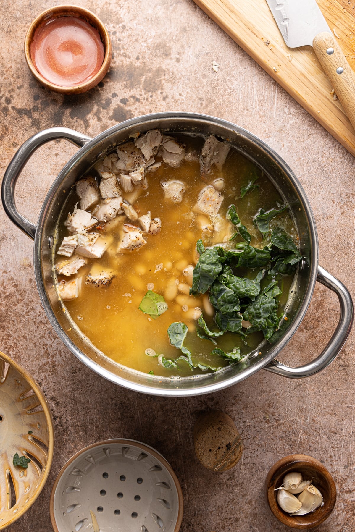 The cubed chicken and kale in the pot with the other ingredients before simmering on the stove.