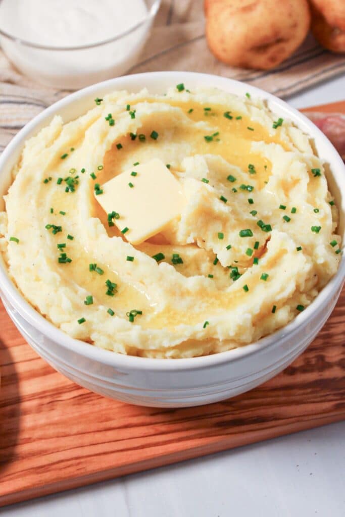 A bowl of cottage cheese mashed potatoes with butter and chives.