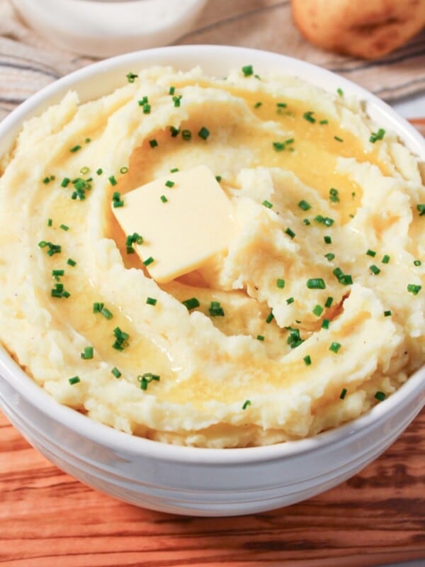 Cottage cheese mashed potatoes in a white bowl with butter and chives.