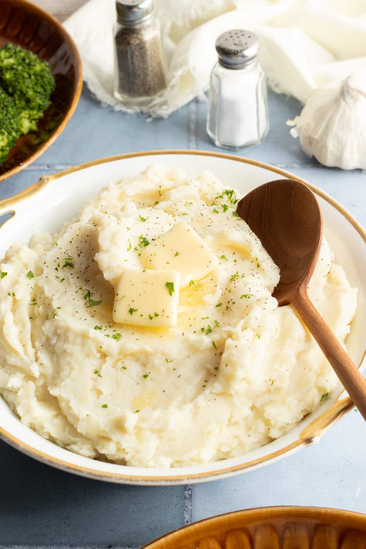 Cottage cheese mashed potatoes in a large bowl with a serving spoon and topped with butter.
