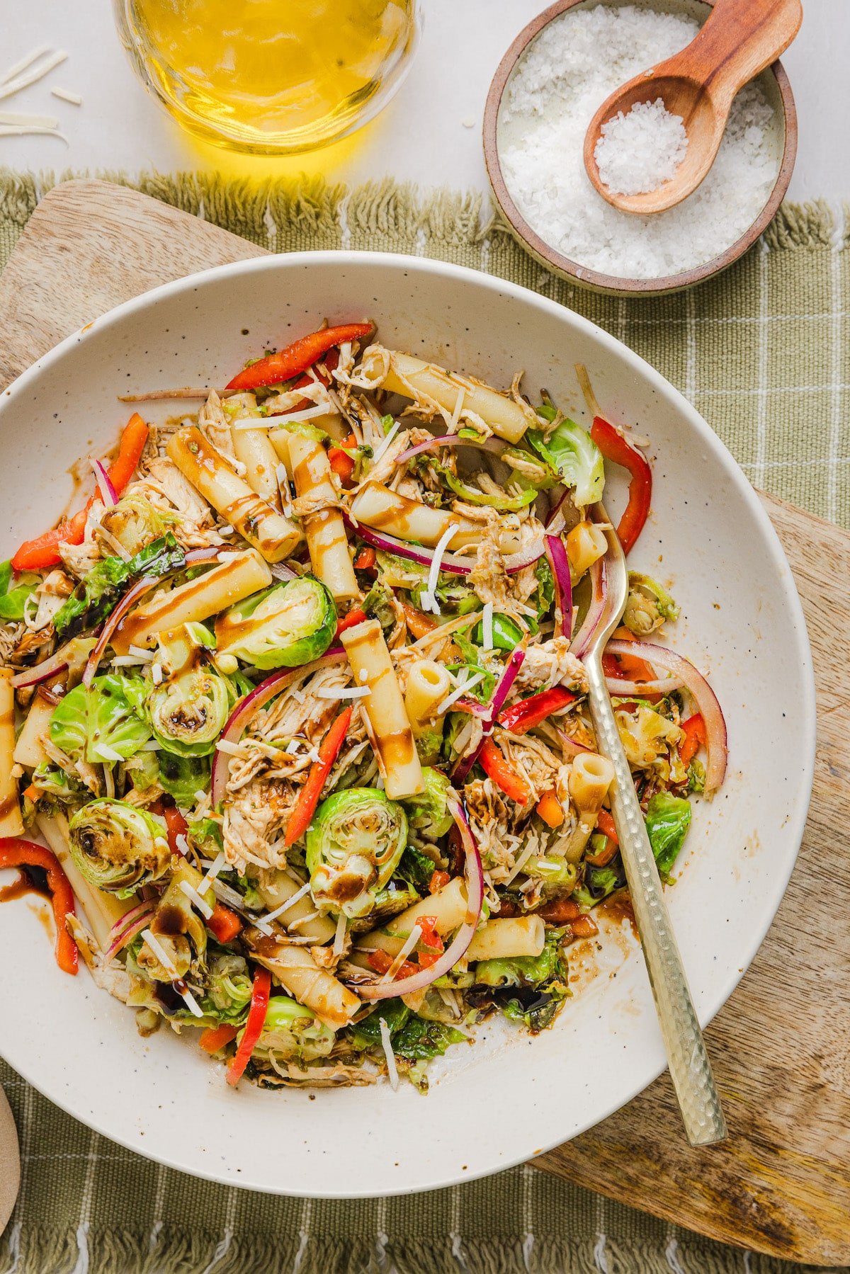 A brussels sprout pasta salad bowl in a bowl drizzled with balsamic glaze.