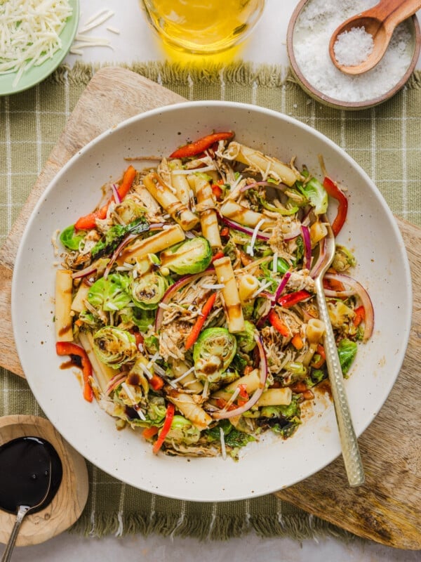 A brussels sprout pasta salad bowl in a bowl drizzled with balsamic glaze.