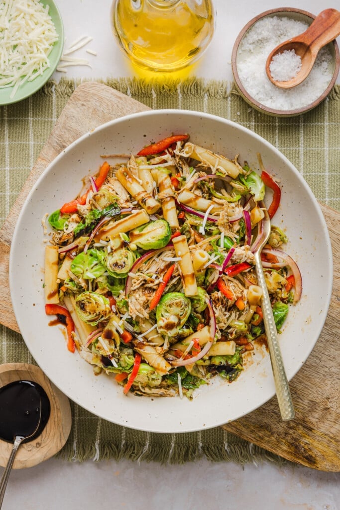 A brussels sprout pasta salad bowl in a bowl drizzled with balsamic glaze.