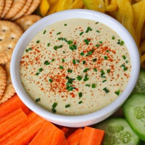 Cottage cheese deviled egg dip in a white bowl with veggies and crackers.