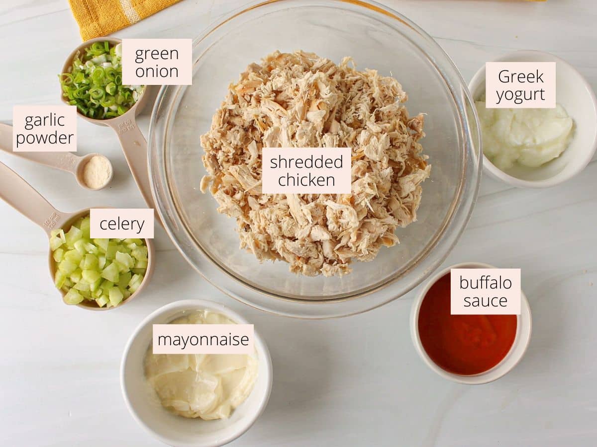 Ingredients for buffalo chicken salad laid out on a white countertop.