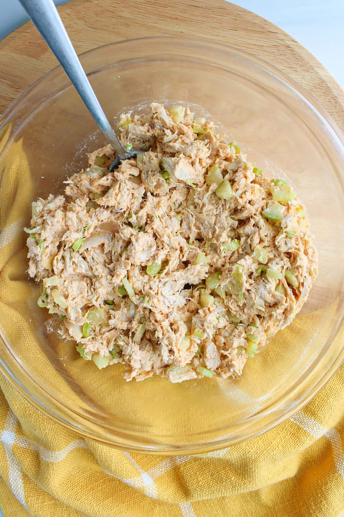 Ingredients for healthy buffalo chicken salad in a clear bowl, mixed.
