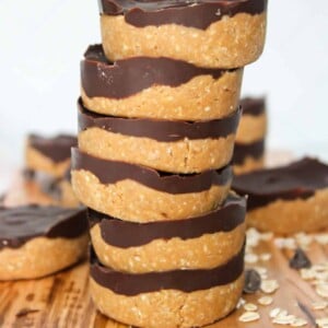 No bake peanut butter oat cups stacked on a wooden board.