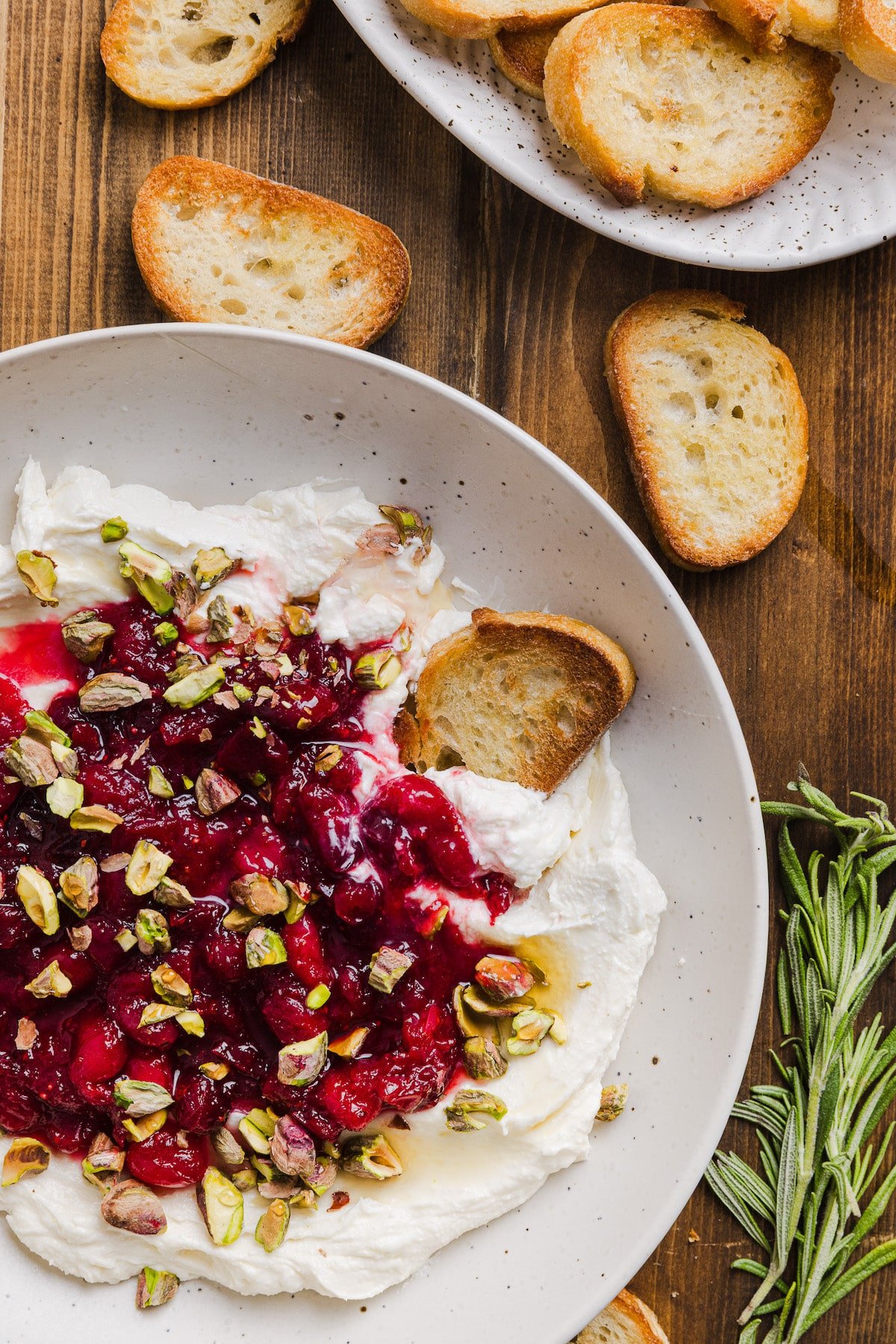 Crostini being dipped into whipped feta cranberry dip.
