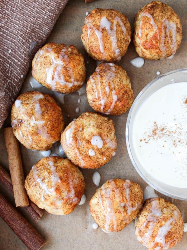 Cinnamon roll bites on parchment paper with a greek yogurt glaze dip.