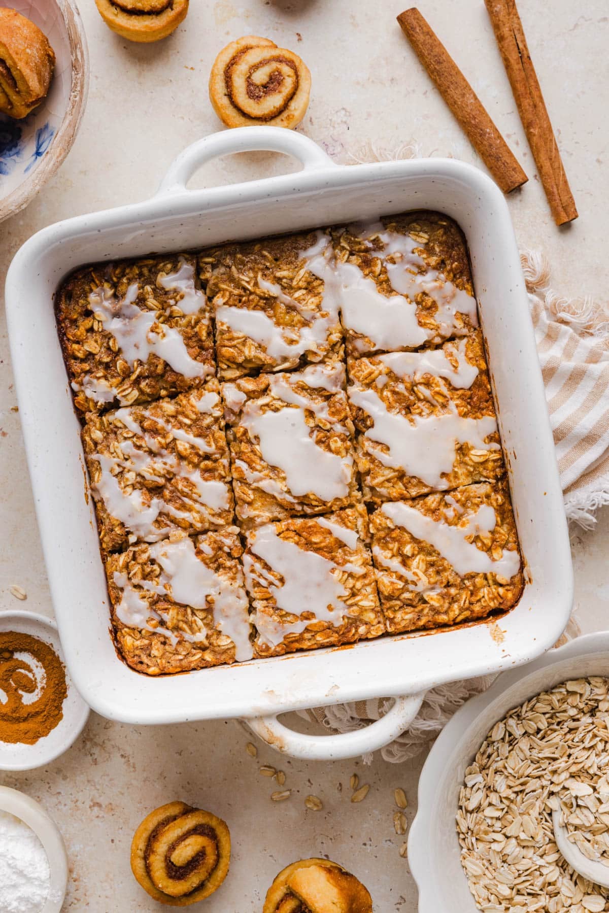 The baked cinnamon toll oatmeal cut into nine squares in the white baking dish on the countertop.