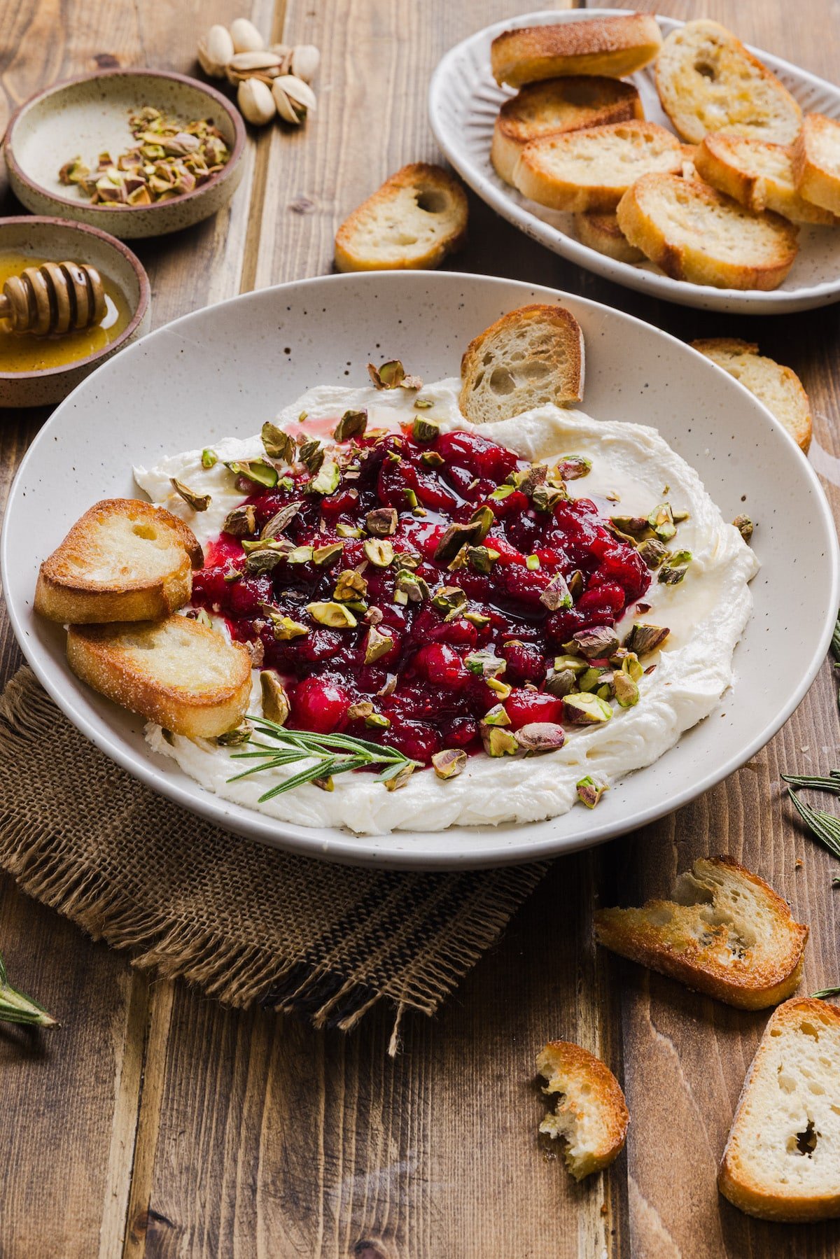 Whipped feta dip in a bowl topped with cranberry sauce and pistachios.