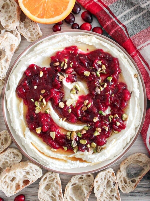 Whipped feta dip topped with homemade cranberry sauce and sprinkled with maple syrup and pistachios.