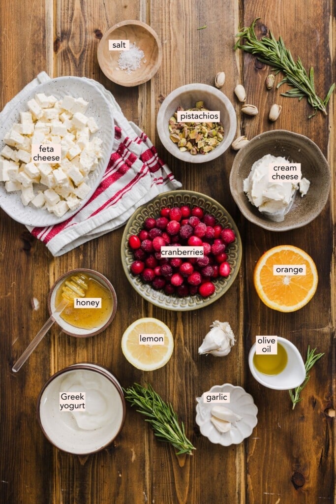 Cranberry whipped feta dip ingredients on a wooden countertop with labels.
