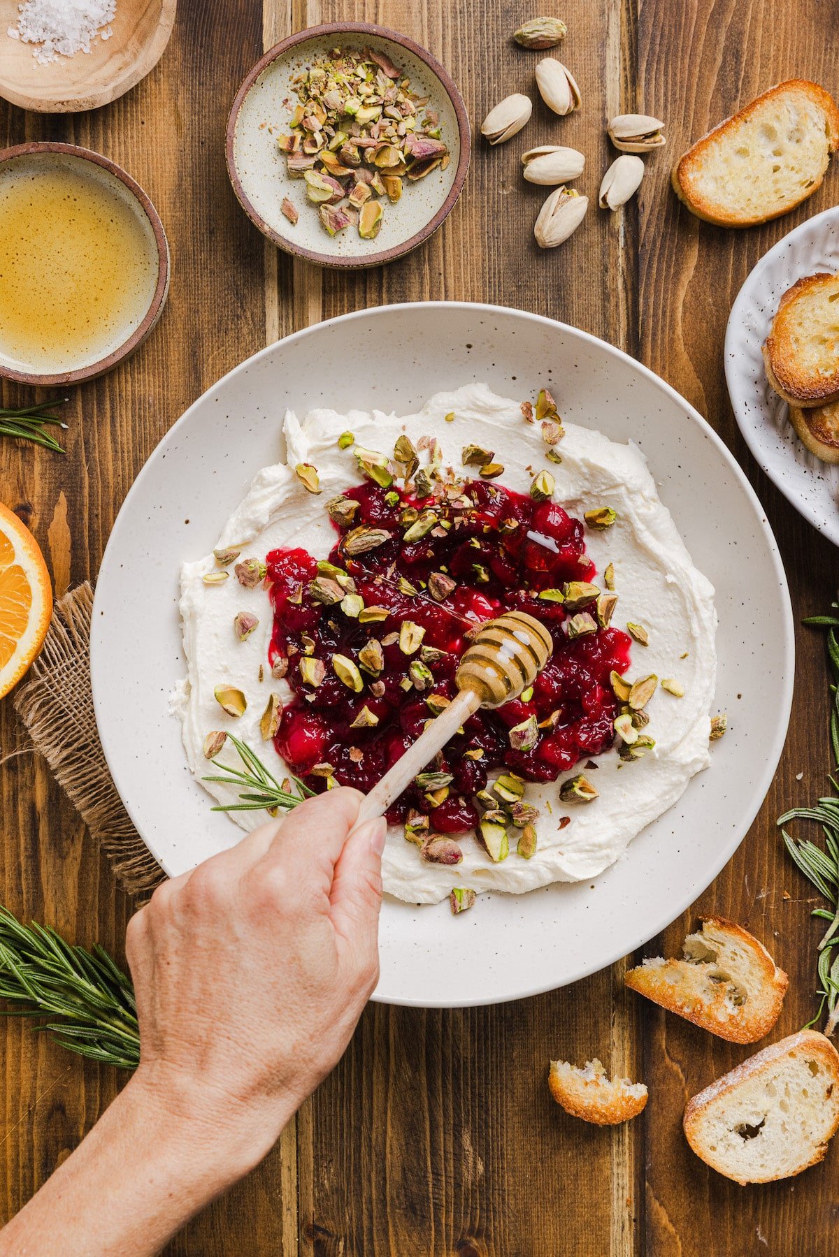 Honey being drizzled on cranberry whipped feta dip.
