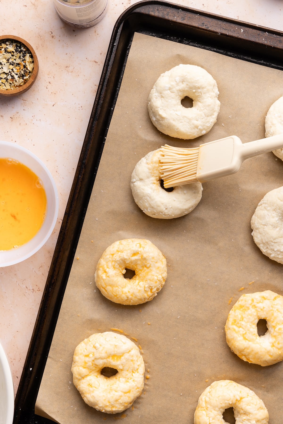 Cottage cheese bagel dough being brushed with egg wash.
