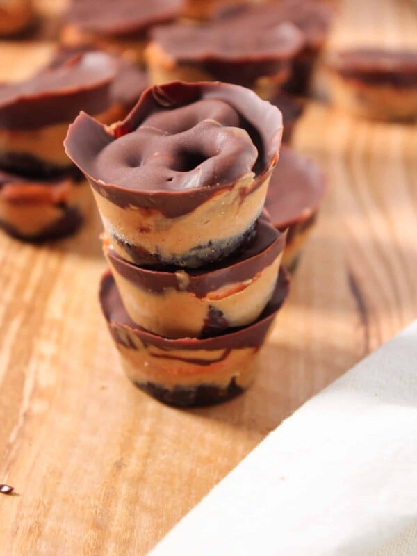 Peanut butter chocolate pretzel date bites stacked on a wooden board.