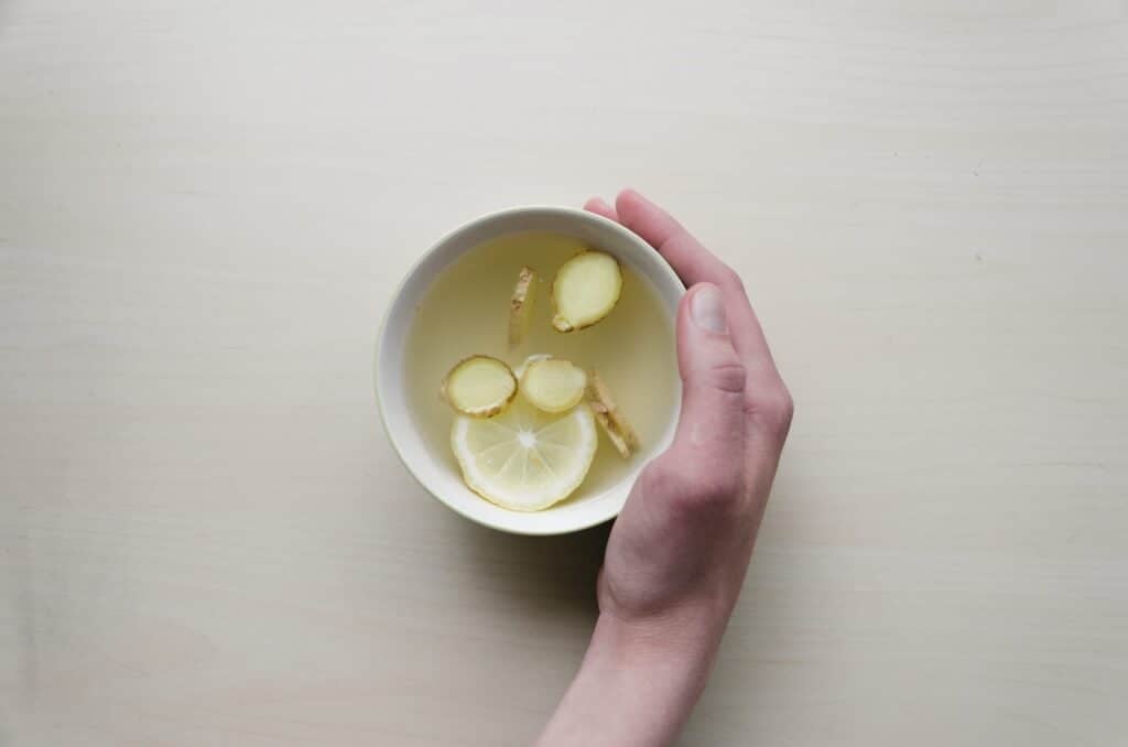 A cup of ginger and lemon tea on a white background. 