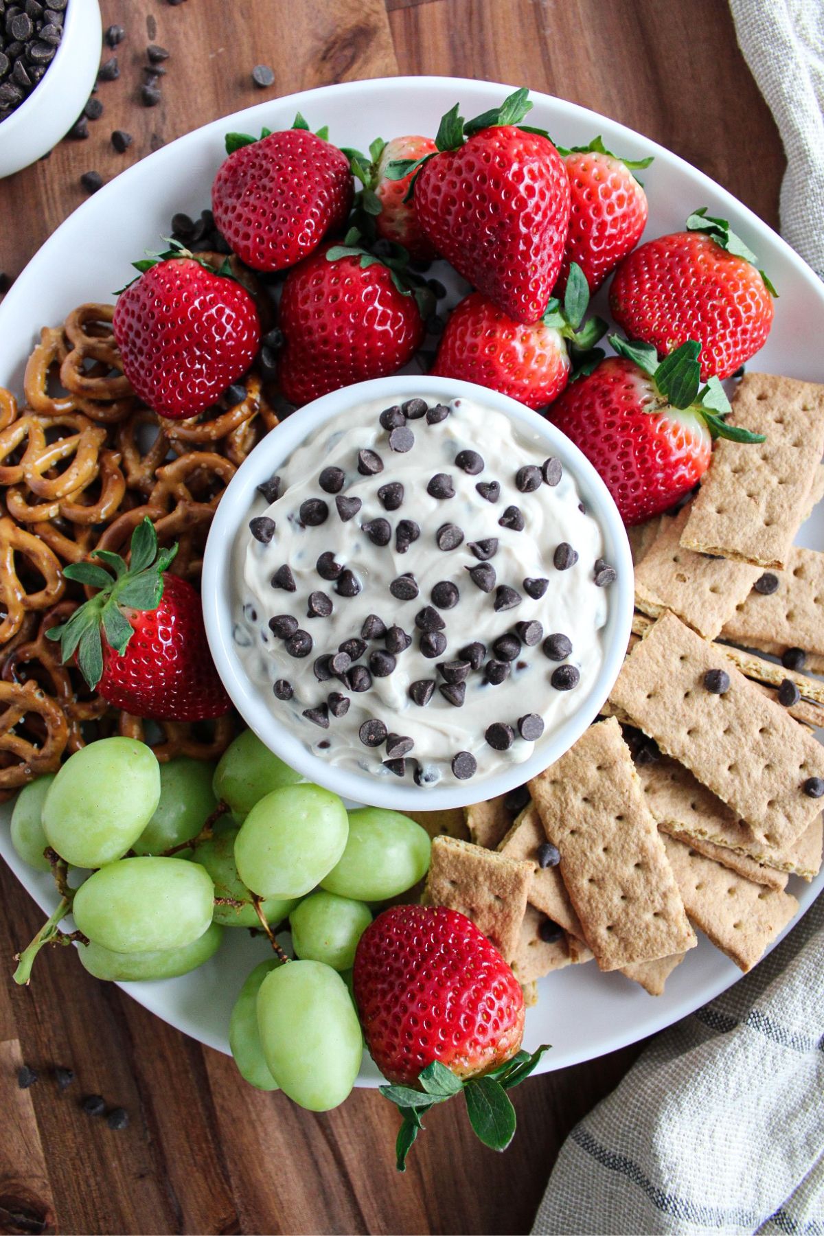 Greek yogurt cookie dough dip surrounded by strawberries, grapes, mini pretzels and graham cracker pieces.
