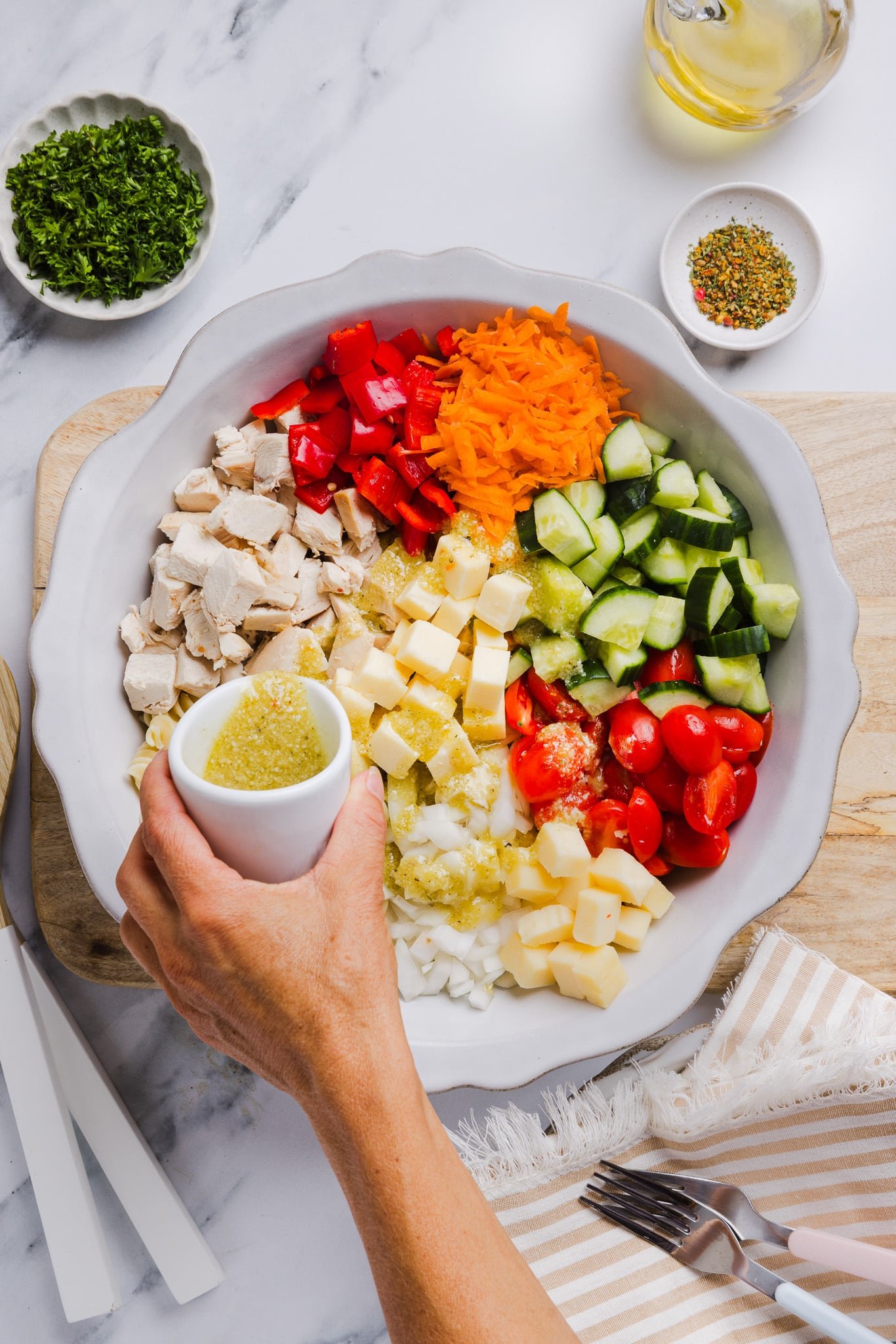 Ingredients for high protein pasta salad in a large bowl with dressing being poured on top.