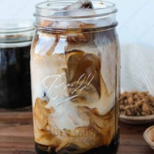 Iced brown sugar coffee and milk swirled in a large mason jar.