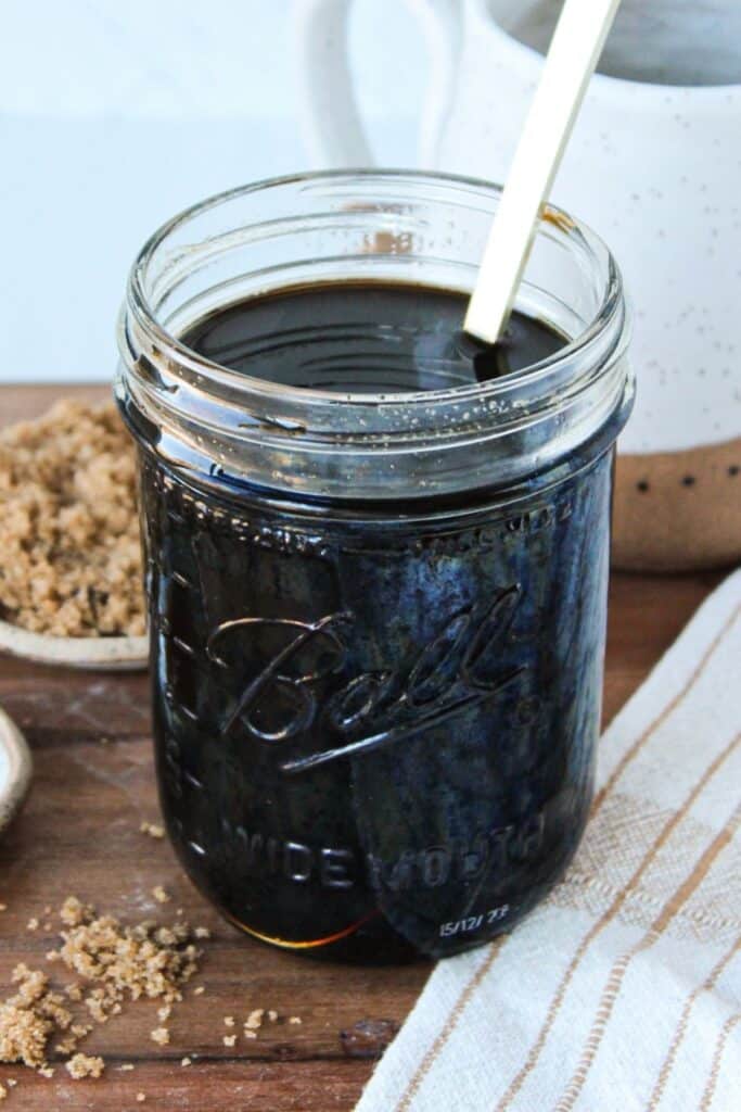 Brown sugar simple syrup in a glass mason jar with a spoon.