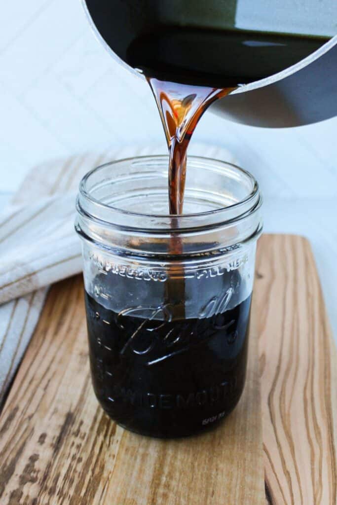 Brown sugar syrup being poured into a mason jar.