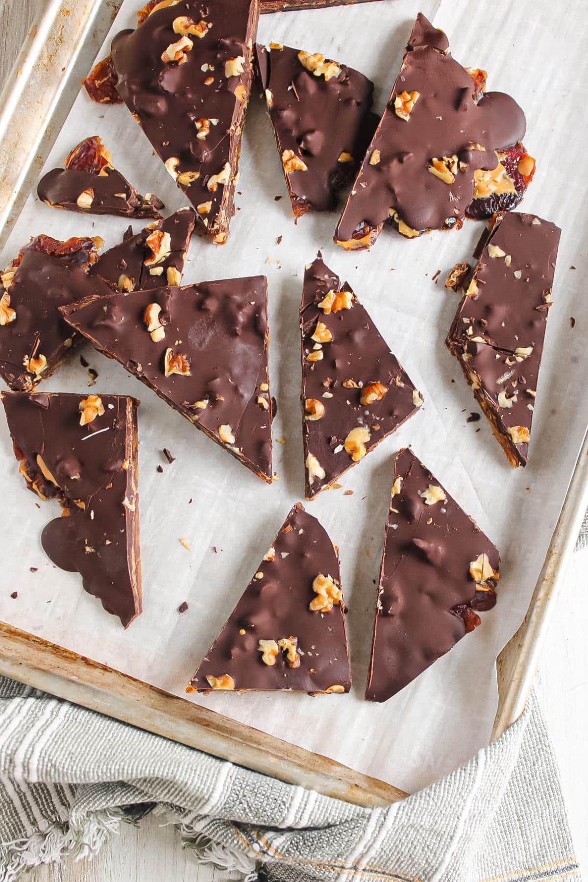 A sheet pan with parchment paper and sliced chocolate date bark.