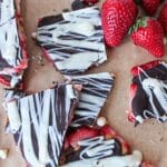 Pieces of chocolate peanut butter strawberry bark on brown parchment paper.