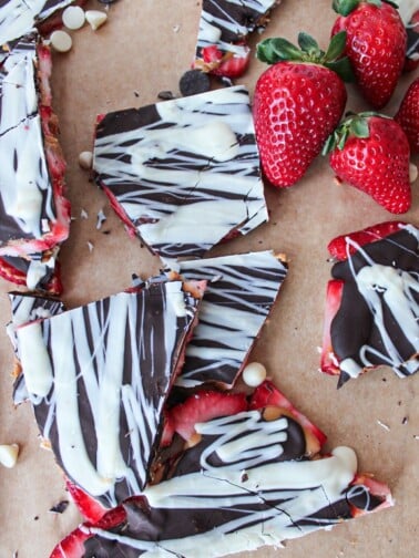 Pieces of chocolate peanut butter strawberry bark on brown parchment paper.