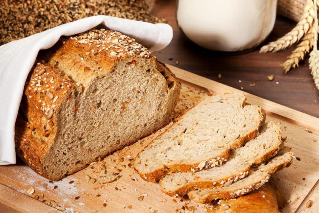 Whole grain bread sliced on a cutting board.