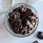 An overhead shot of dark chocolate covered almonds in a glass mason jar.