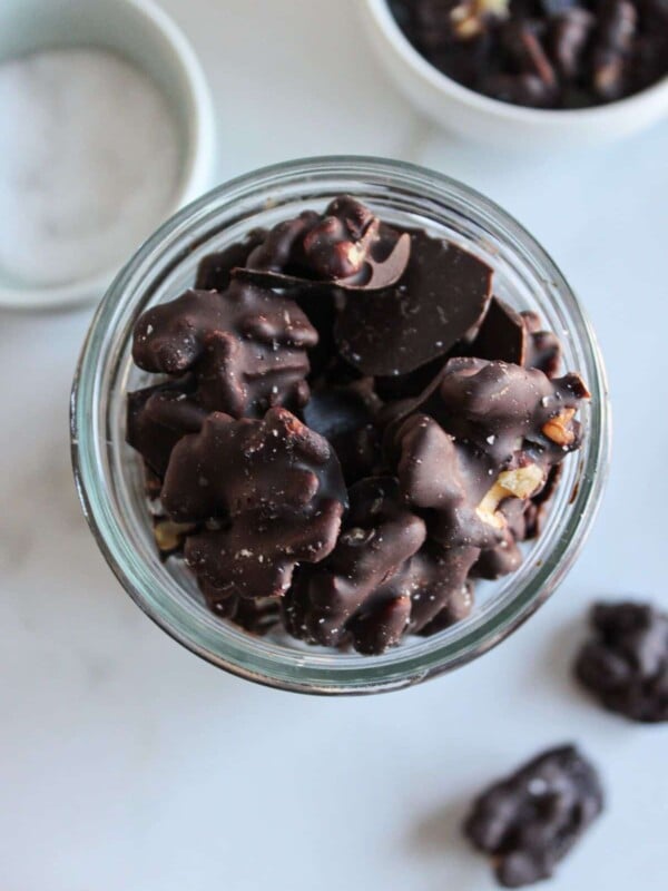 An overhead shot of dark chocolate covered almonds in a glass mason jar.