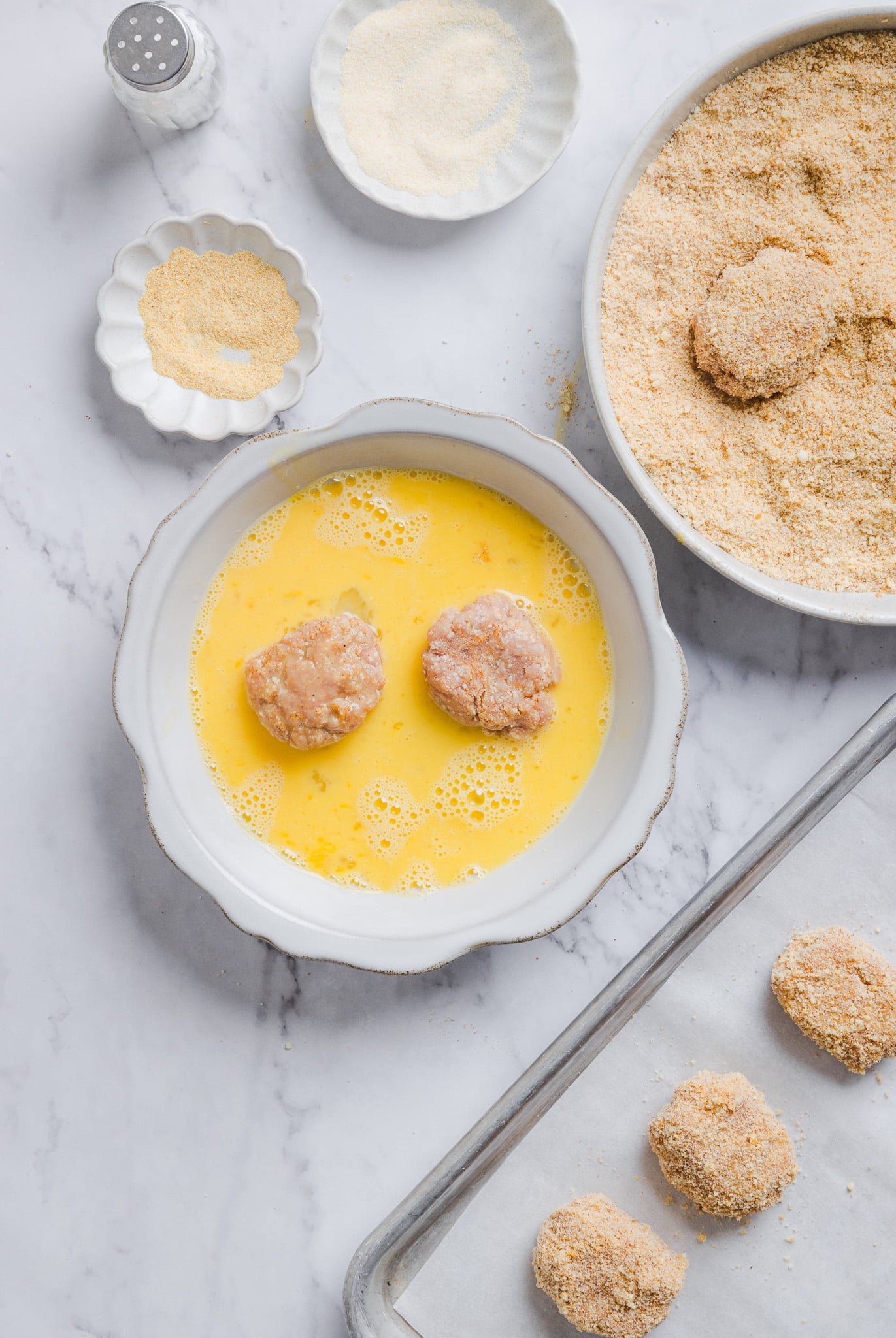 Ground chicken nuggets being dunked in egg wash.