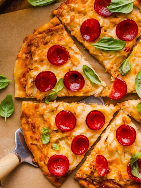 A high protein pizza sliced into slices on a brown piece of parchment paper.