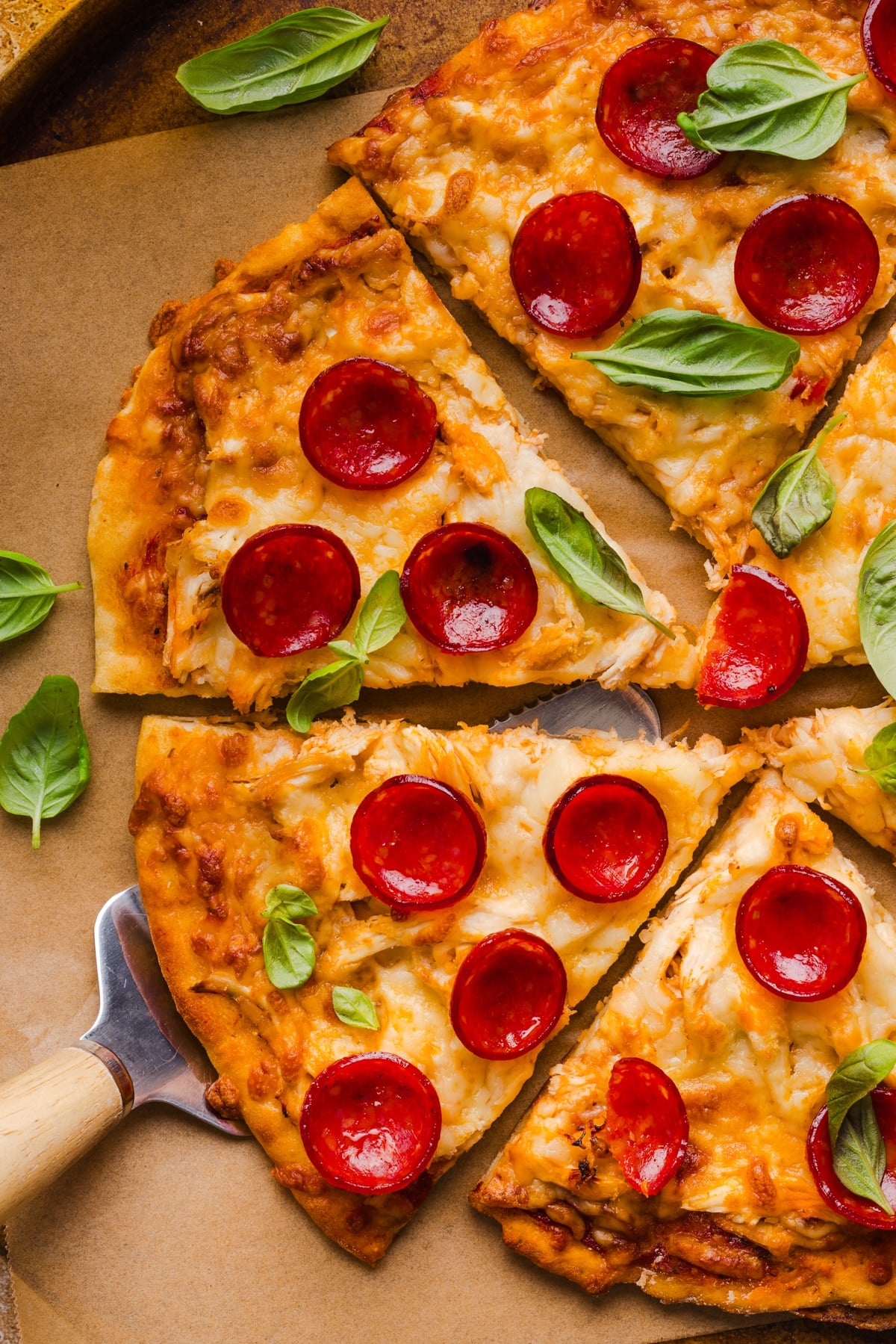 A high protein pizza sliced into slices on a brown piece of parchment paper.