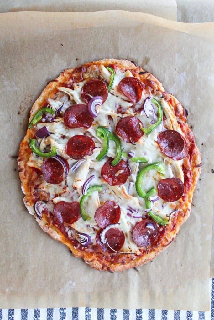 Freshly baked high protein pizza on a piece of parchment paper.
