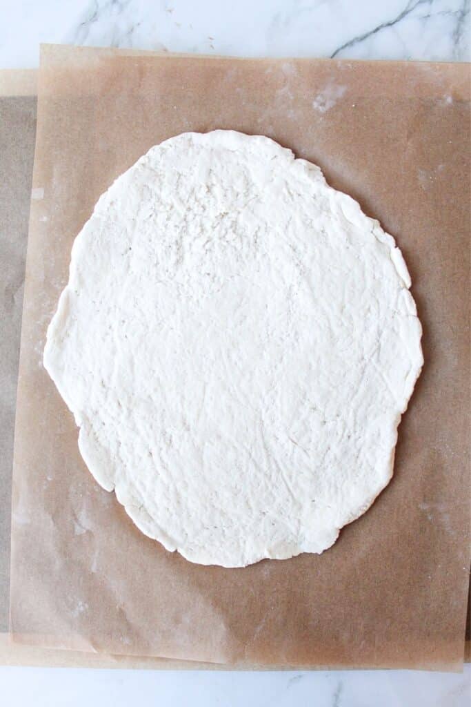 Rolled out high protein pizza dough on a piece of parchment paper.
