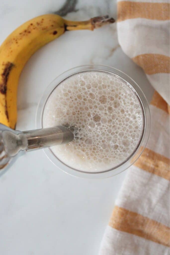 Ninja creami banana ice cream ingredients being blended with an immersion blender.