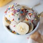 A small white bowl of Ninja creami banana ice cream with colorful sprinkles.