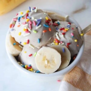 A small white bowl of Ninja creami banana ice cream with colorful sprinkles.
