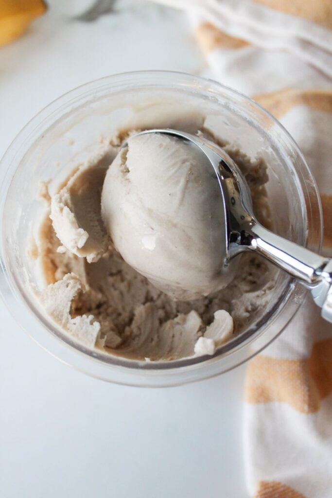 A close up shot of a scoop of Ninja Creami banana ice cream in a pint container.