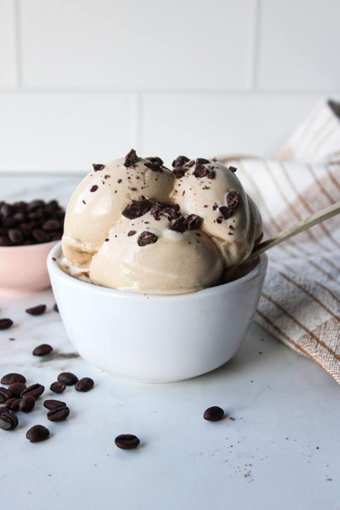 Ninja creami coffee ice cream in a white bowl with chocolate chunks.